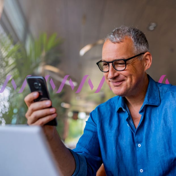 Future of Networks Blog (Spain) Header Photo of a smiling, casually dressed man reading something on his cellphone. In the background, a series of small purple wave forms run across the frame, representing communications.