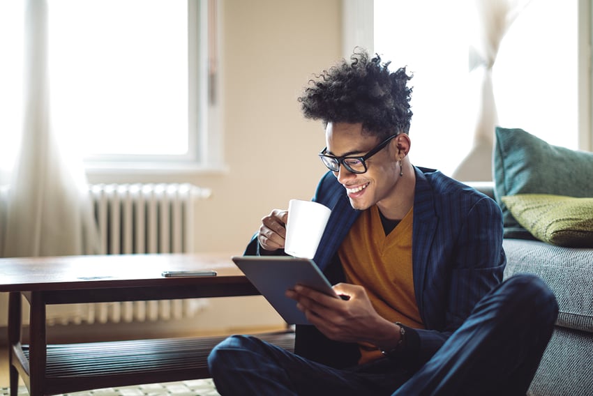 Man sitting on floor working remote enjoying coffee and on his smart device