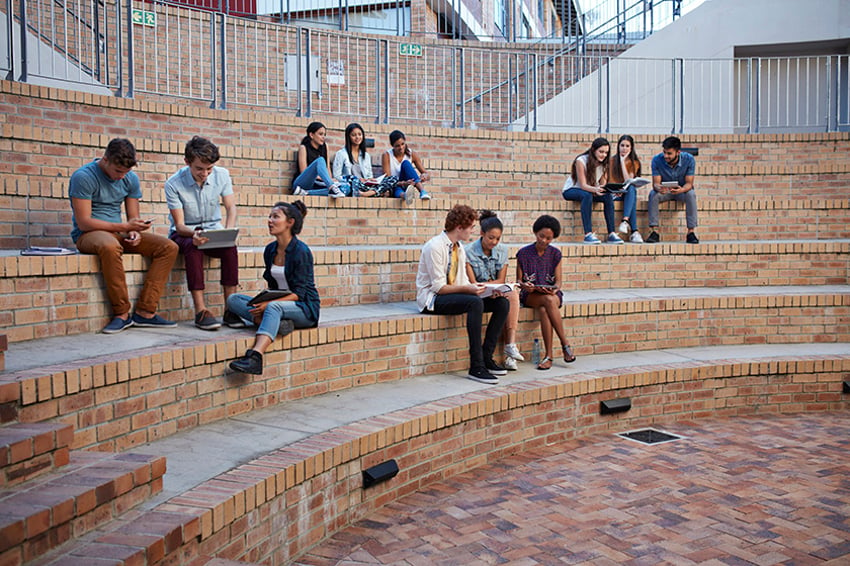 Alumnos estudiando en grupos en exteriores, en el campus