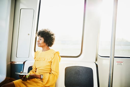 woman sitting on public transportation holding phone