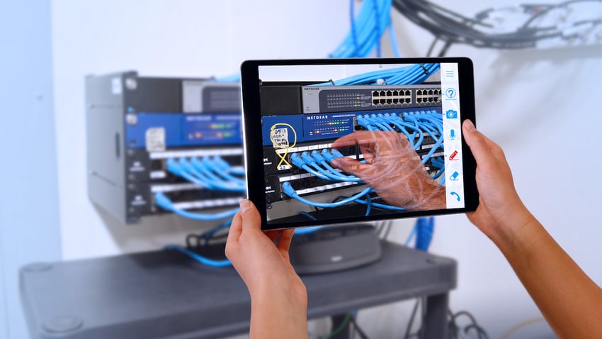 Remote help for network troubleshooting via Help Lightning hands holding up a tablet to show a remote help agent the back of a computer network